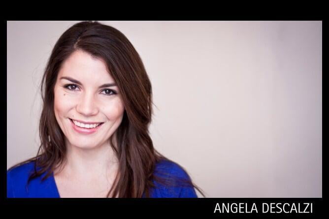 Angie Descalzi, a Latinx woman, wearing an electric blue sweater and smiling to the camera with her head slightly tilted to the right. She has long, brown hair parted to one side. 