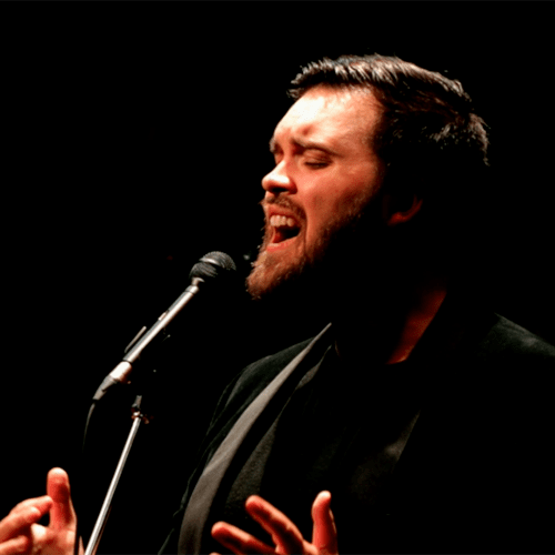 Headshot of Corey Payette singing at a microphone
